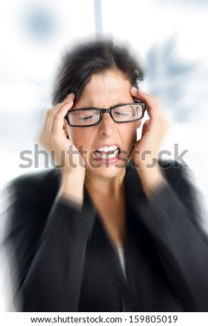 Businesswoman with intense stress and painful headache. Woman with glasses in job problems.