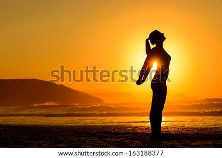 Fit Woman Doing Yoga Relaxing And Breathing Exercises On Beach At Sunset. Freedom, Relax And Harmony In Nature. Female Stretching Arms Alone.