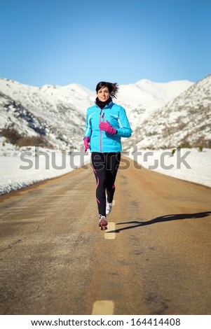 Woman Running Fast In Country Winter Mountain Road. Female Runner Training Endurance Outdoor In Cold Weather.