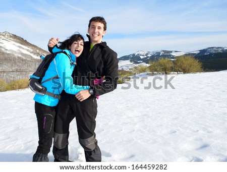 Happy couple on winter hiking trip to mountain. Man and woman having fun, laughing and enjoying on snow outdoors.