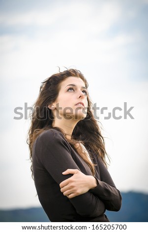 Sad pensive woman shivering, hugging herself and feeling low. Female emotional depression and sadness. Curly hair caucasian model.