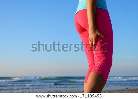 Female runner suffering from a painful hamstring muscle contracture or spasm during training. Sport leg injury during running concept.