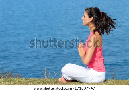 Woman doing yoga breathing and relaxing exercise by the sea. Relax and meditation concept.