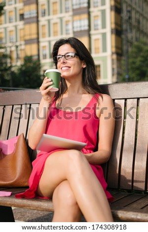 Successful casual businesswoman using digital tablet and drinking coffee outside. Modern woman enjoy the freedom of working with digital devices.