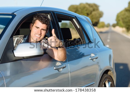 Successful man driving car and doing thumbs up. Cheerful male driver approving.