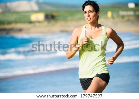 Fitness woman running fast on beach.