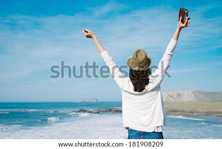 Hipster woman enjoy freedom on vacation travel. Successful funky girl raising arms towards the sea.