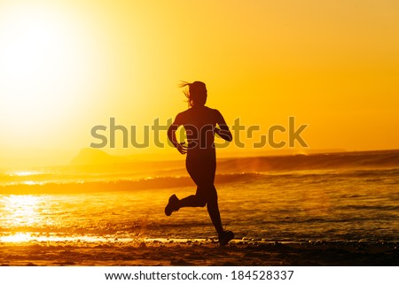 Female runner training hard on beautiful summer sunset or morning. Woman running fast at the beach.