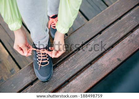 Fitness woman lacing running sport shoes before workout on rainy day.