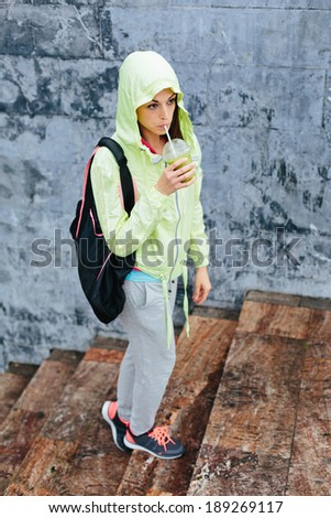 Urban fitness woman drinking vegetable detox smoothie after workout outside.