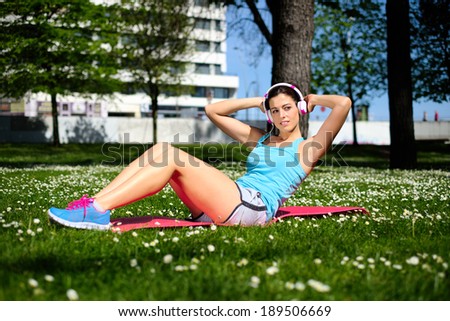 Fit woman working out doing sit ups fitness exercises in city park on spring or summer. Beautiful fitness girl during crunches workout.