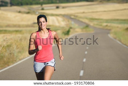 Female athlete on running workout in country road . Fit sporty runner training on summer.