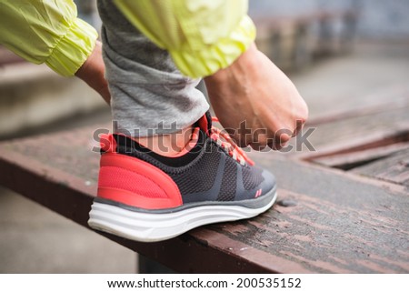 Female runner tying sport shoes laces before running urban challenge. Sporty unrecognizable woman lacing footwear getting ready for training. Fitness and healthy lifestyle concept.