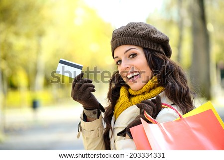 Fashion trendy woman showing credit card and carrying shopping bags after buying on autumn. Caucasian brunette shopper spending money.