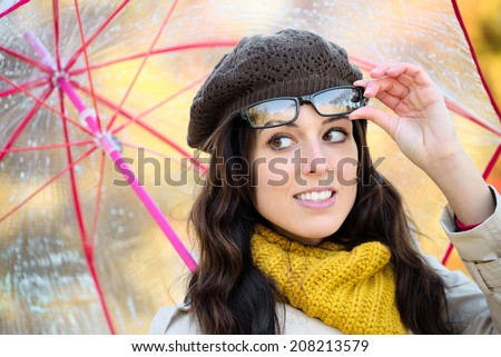 Woman autumn portrait wearing glasses and holding umbrella in rainy day. Fashionable cheerful female with eyewear outside.