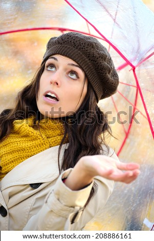 Woman checking with hand if it is raining in autumn. Brunette female worried because of bad weather.