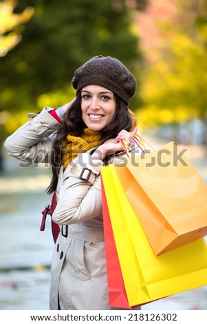 Woman with shopping bags walking in autumn. Fashion female shopper outside.