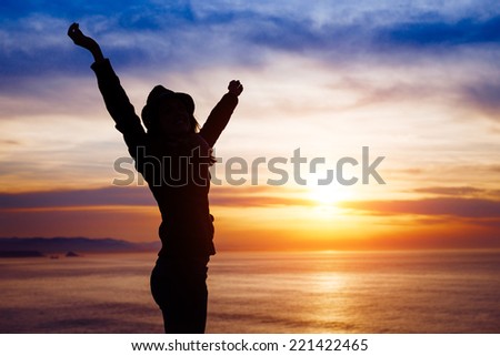 Blissful woman enjoying freedom and happiness on beautiful sunset towards the ocean and sky.