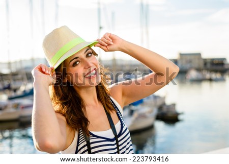 Joyful beautiful tourist at sport harbor of Gijon, Asturias, Spain. Woman enjoying summer vacation travel.