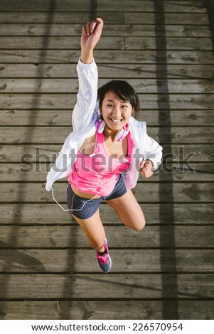 Successful young sporty woman jumping with arm up. Asian female athlete in manga looking happy action. Success in sport and healthy lifestyle concept.