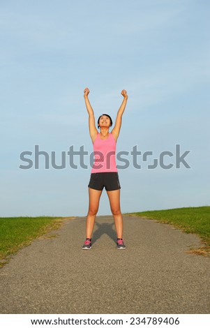 Successful asian athlete raising arms for celebrating running work out goals.