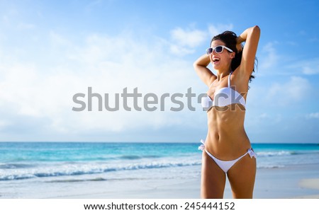 Beautiful joyful woman in white bikini enjoying tropical beach and caribbean summer vacation. Tanned brunette running free by the sea at Playa Paraiso, Riviera Maya, Mexico.