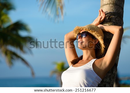 Woman on caribbean travel relaxing and resting under tropical palm trees. Happy brunette enjoying vacation and tranquility.