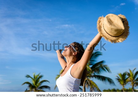 Blissful woman on tropical caribbean vacation raising arms to the sky. Freedom and travel concept. Brunette woman enjoying summer holidays.