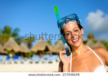 Happy woman on caribbean tropical travel and vacation wearing snorkel gear. Cheerful brunette enjoying sport sea activity on resort beach. Mayan Riviera, Mexico.