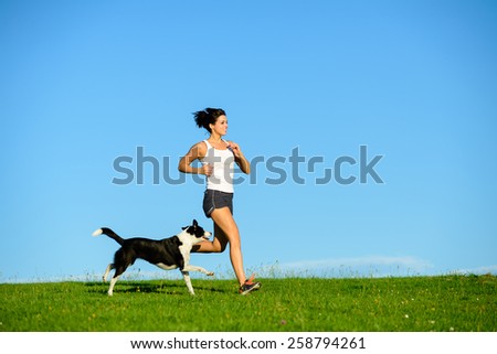 Woman and dog running and exercising outdoor at grass field on summer or spring. Happy female athlete training with her pet.