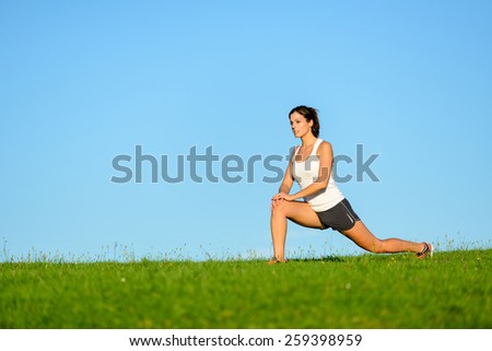 Sporty woman stretching legs and exercising. Fitness brunette girl on outdoor workout.