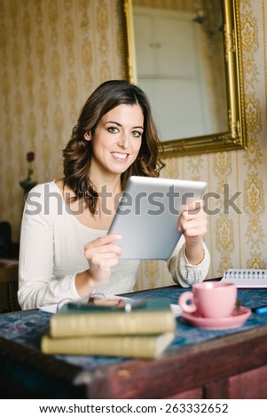 Woman at vintage looking home working and reading on digital tablet. Female young worker or student doing her job in retro desk.