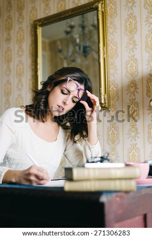 Woman working at home. Female entrepreneur writing and studying. Female young worker or student doing her job in retro desk. Vintage filtered image.