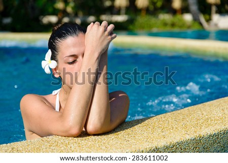 Beautiful relaxed woman in white bikini enjoying spa pool at resort. Beauty and body care concept.