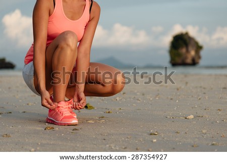 Woman lacing sport shoes and getting ready for running and exercising at beach on summer, Krabi, Thailand. Fitness woman training outdoor.