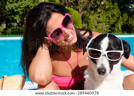 Happy woman and dog wearing sunglasses and having fun on summer vacation at swimming pool.