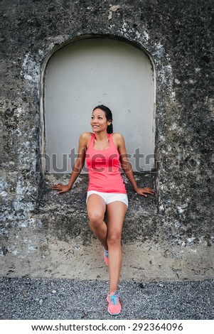 Happy sporty fitness woman taking a workout break outdoor. Hispanic female athlete full body portrait.