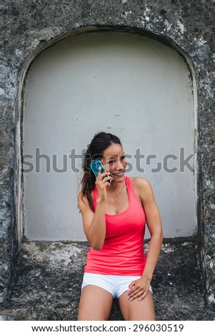 Fitness woman talking on cellphone during a training break outdoor. Female athlete taking a rest for phone call.