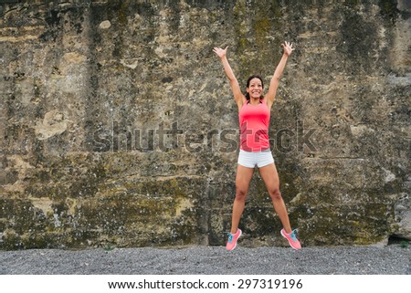 Happy female athlete jumping for celebrating exercising and fitness success.