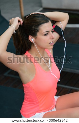 Sporty woman getting ready for fitness exercising workout. Beautiful sporty model wearing earphones for motivation.