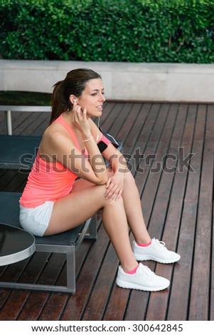 Motivated sporty woman relaxing before  outdoor fitness workout. Female athlete taking a training break for resting.