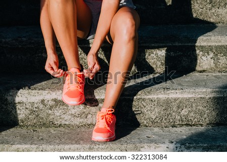 Woman lacing running and sport shoes. Sporty footwear close up. Fitness motivation and healthy lifestyle concept.