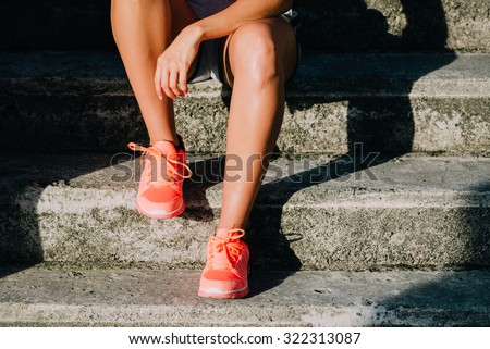 Woman taking a workout rest. Sporty and running footwear close up. Fitness motivation and healthy lifestyle concept.