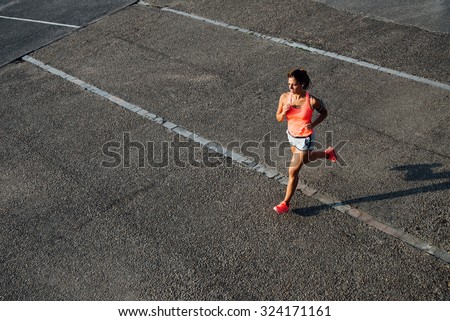 Top view of woman running on city asphalt. Female runner training outdoor.