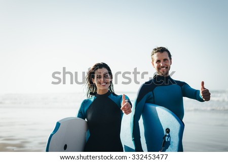 Successful couple of surfers. Surfing and outdoor sport lifestyle concept. Woman and man after bodyboarding.
