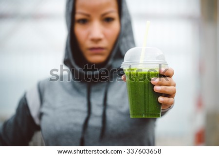 Fitness diet and nutrition concept. Tough looking urban sporty woman taking a rest for drinking nutritive detox smoothie.