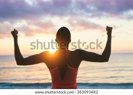 Fitness woman celebrating fitness workout success and motivation towards the sea and sunset.