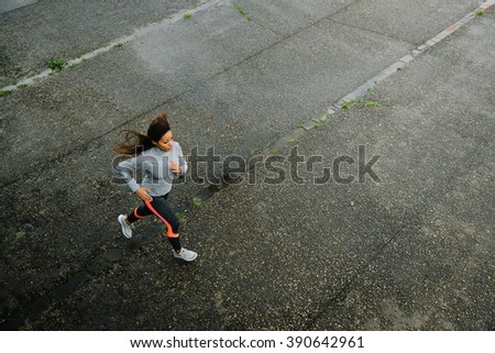 Top view of fit female athletes running on rainy day. Woman exercising outdoor on urban asphalt.