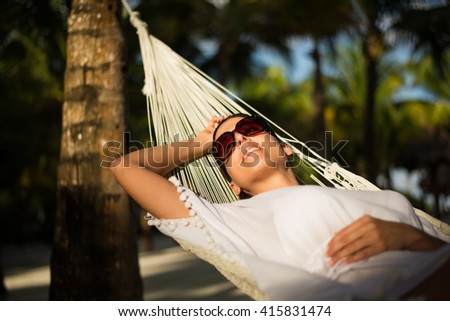 Tranquil woman relaxing lying on a hammock at tropical beach. Summer vacation relax and tranquility concept. Relaxed female resting outdoor.