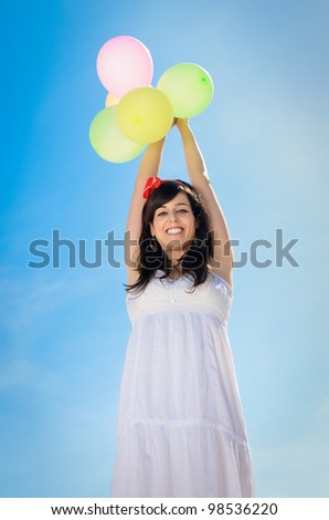 Happy girl on spring season with balloons on blue sky background. Woman Bliss and freedom copy space.